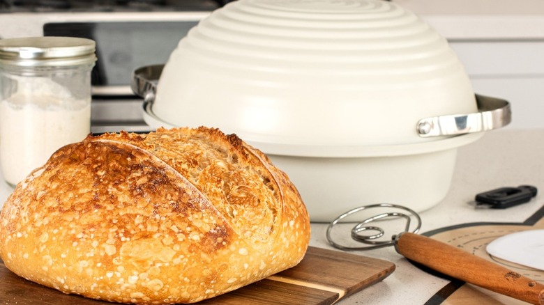 Loaf of sourdough bread with bread maker in background
