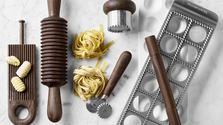 Assorted pasta making tools laid out on white granite countertop.
