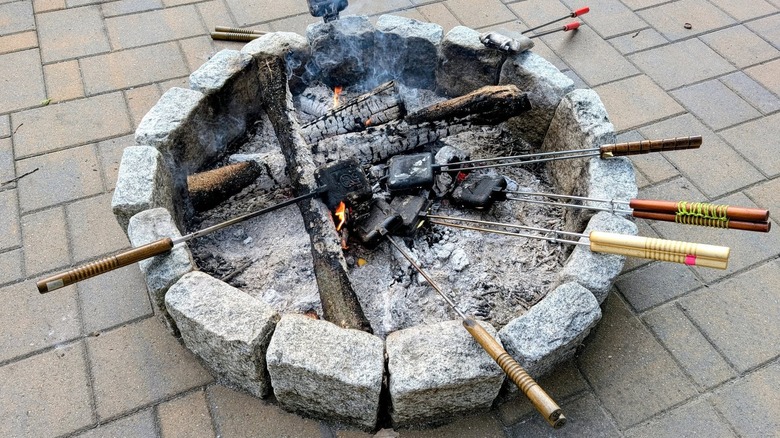 Several mountain pie makers in a fire pit