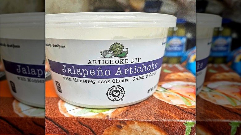 Tub of Aldi's Park Street Jalapeño Artichoke Dip on a box of crackers