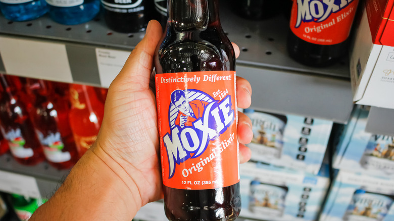 Person holding a bottle of the Moxie Original Elixir drink