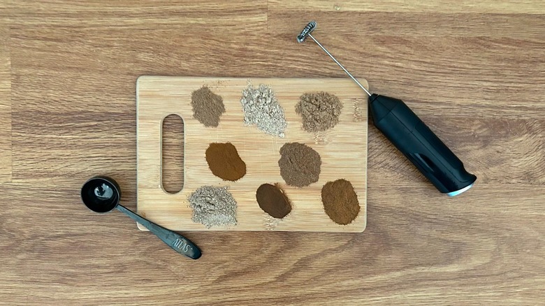 Wooden cutting board with various mushroom coffee powders on it, scooper, and mini frother