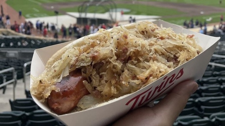 A person holding a sausage with sauerkraut at Target Field