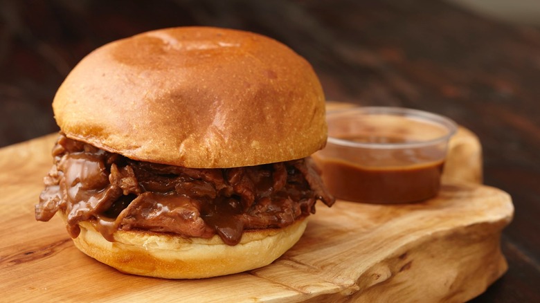 A Lobel's USDA Prime Steak Sandwich with gravy on a thick, wooden board