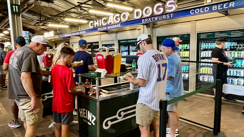 People dressing hot dogs at a condiment station at Wrigley Field