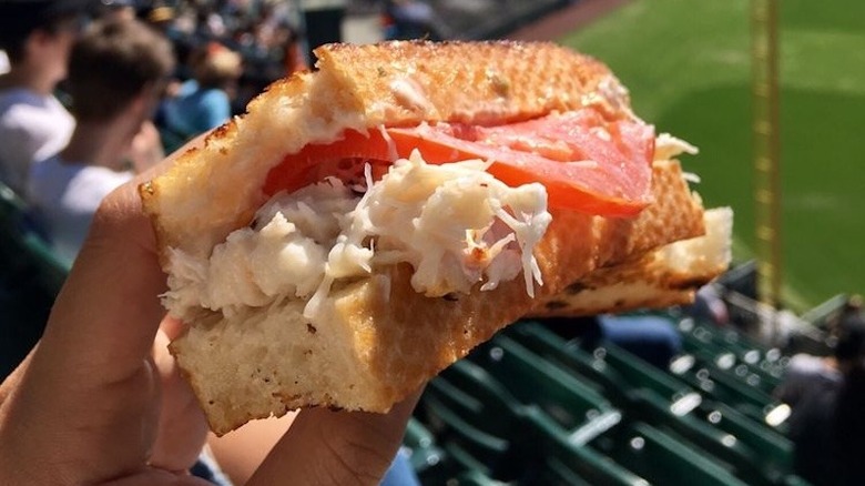 A person holding a Crazy Crab'z Sandwich at Oracle Stadium