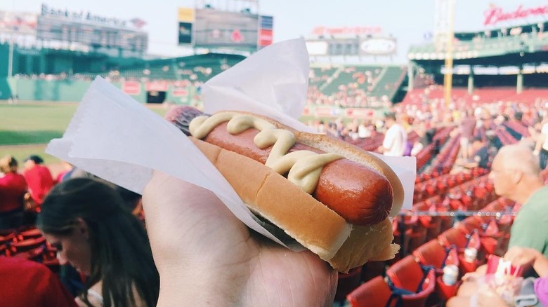 A person holding a Fenway Frank at Fenway Park