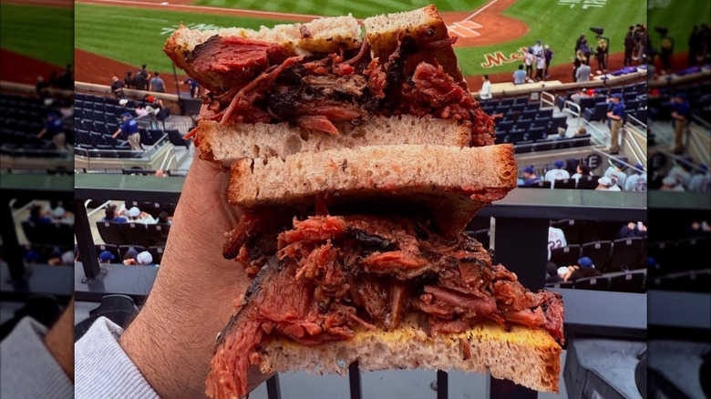 A person holding a Hot Pastrami sandwich at Citi Field