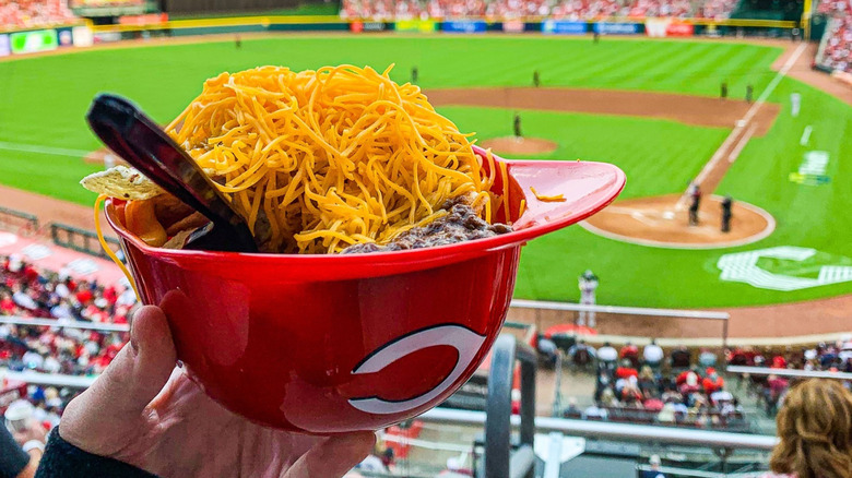 A person holding a red plastic helmet filled with Skyline Chili at Great American Ball Park