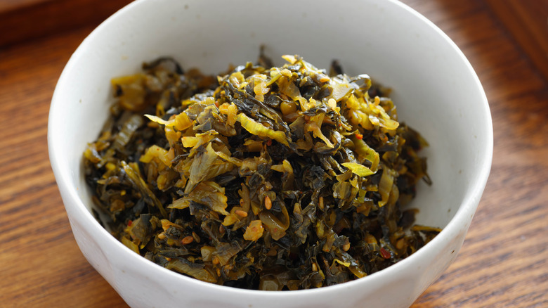 Stir-fried pickled mustard greens in white bowl.