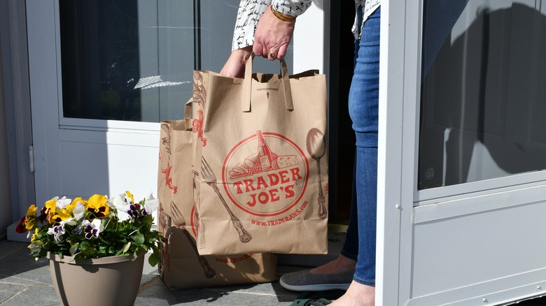 Person picking up Trader Joe's brown paper shopping bags