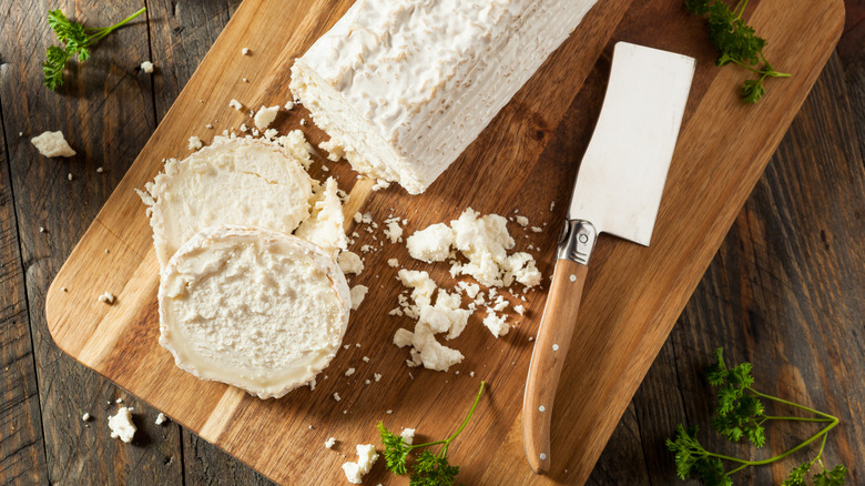 Sliced goat cheese on cutting board