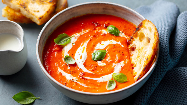 Bowl of tomato soup with bread and garnish