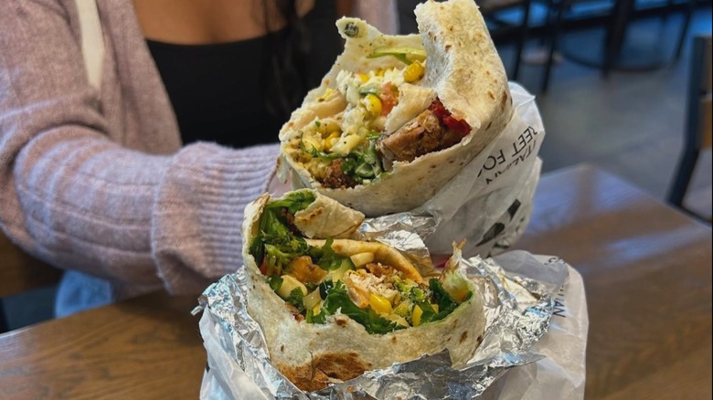 People holding two burritos next to each other