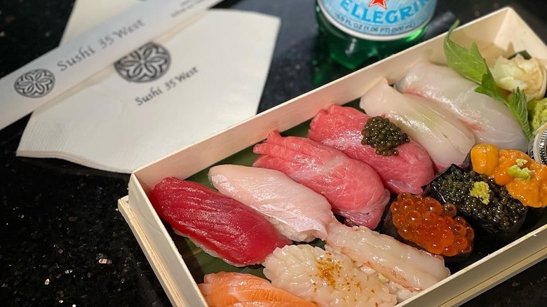 A box of mixed nigiri beside a napkin and chopsticks.