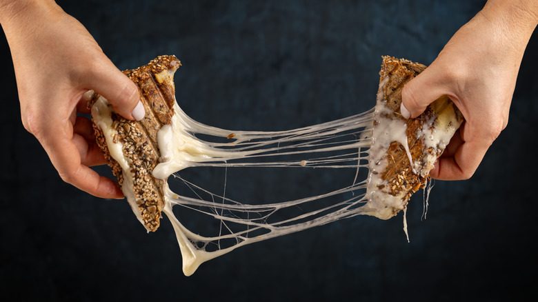 hands pulling apart grilled cheese