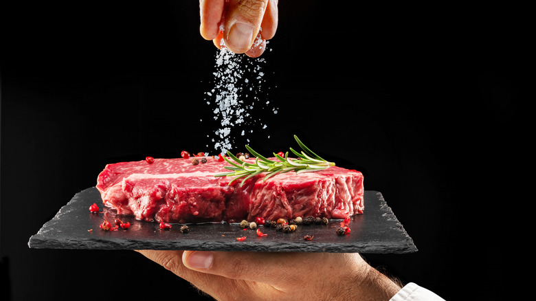 Chef salting a raw steak