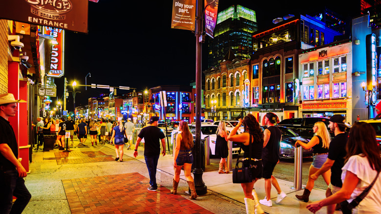 Tourists walk through downtown Nashville on Broadway at night