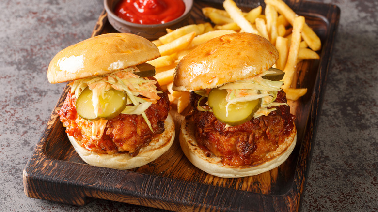 Two Nashville hot chicken sandwiches rest on a board