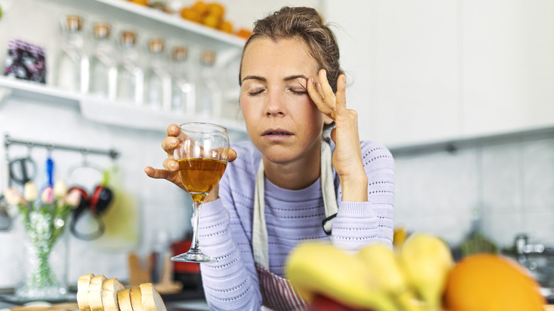 woman with headache holding wine