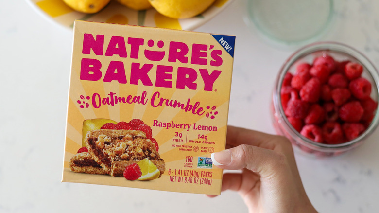 Person holding a box of Nature's Bakery Oatmeal Crumble Raspberry Lemon Bars