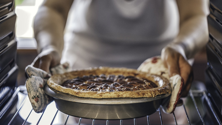 Hands pulling a pie out of an oven