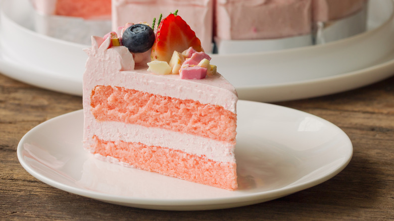 Pink, layered strawberry cake topped with berries
