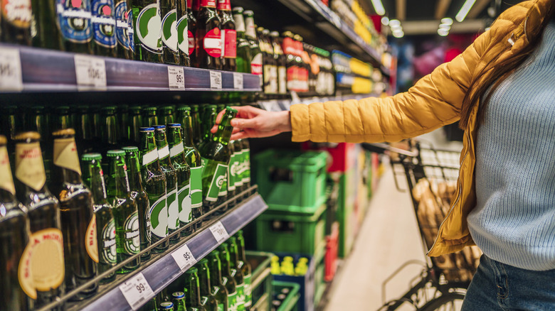 Woman looking at beer on grocery store shelf