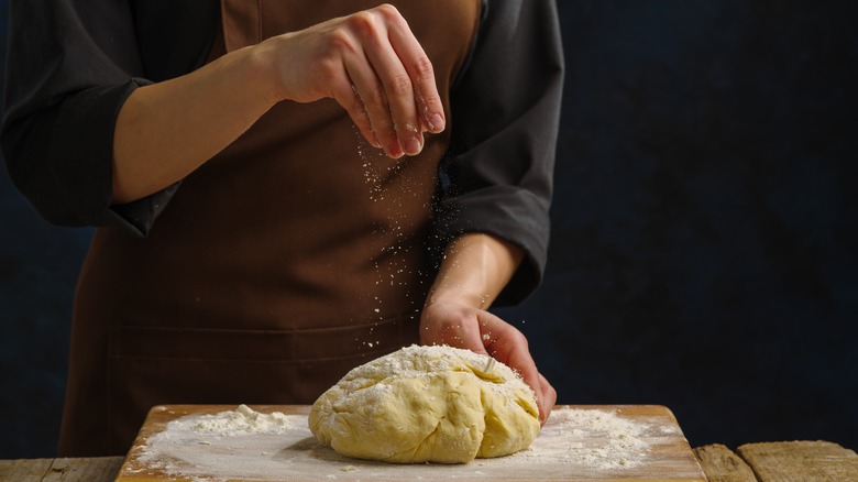 Someone sprinkling flour over dough