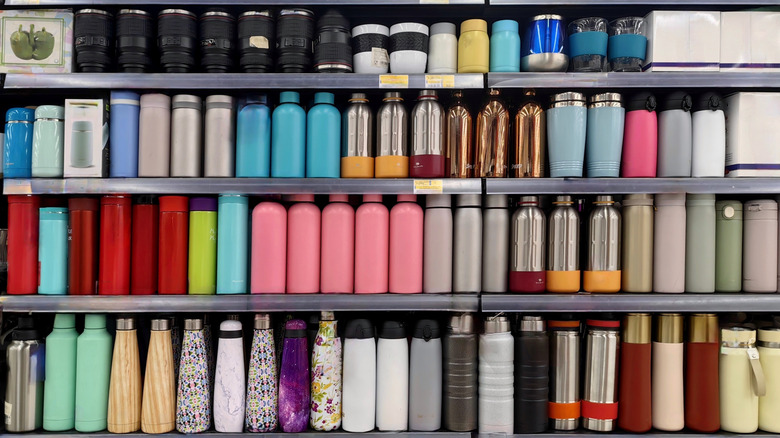 The store shelves are full of a variety of drinking bottles and thermoses in different colors, materials, and designs.
