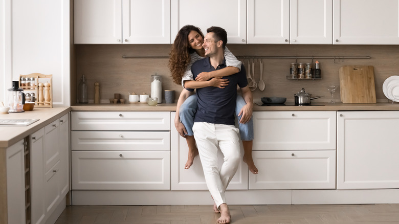 Man and woman smiling in a modern-style, plain kitchen