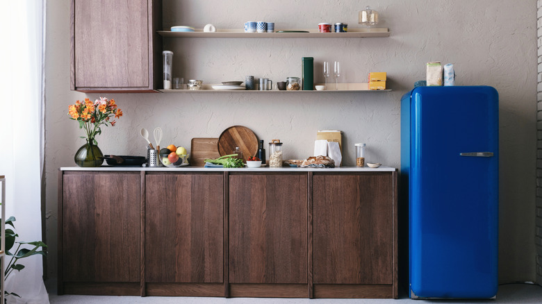 A kitchen with brown wooden cabinets, air shelves, and a blue retro-style refrigerator
