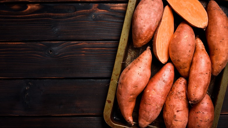 Raw sweet potatoes on a metal tray.