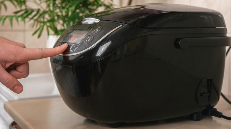 Person pressing button on slow cooker