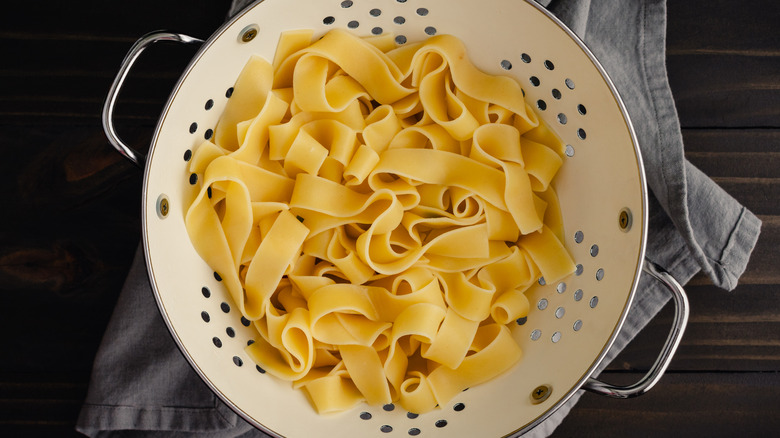 Boiled and strained broad noodles in an enameled metal colander