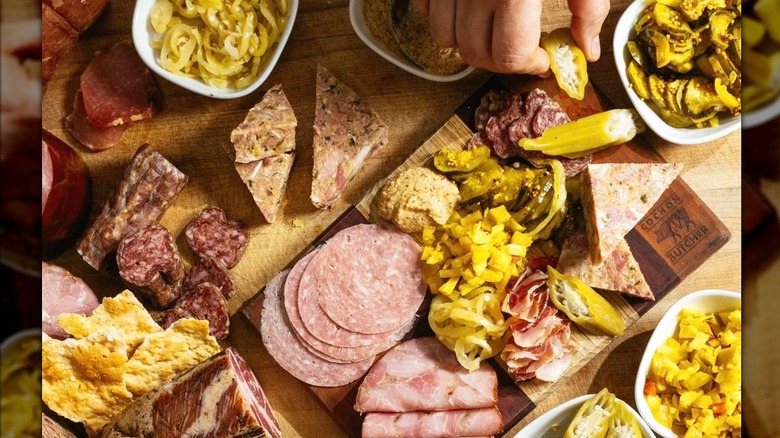 Hand reaching for a stuffed pepper on a charcuterie board from Cochon Butcher