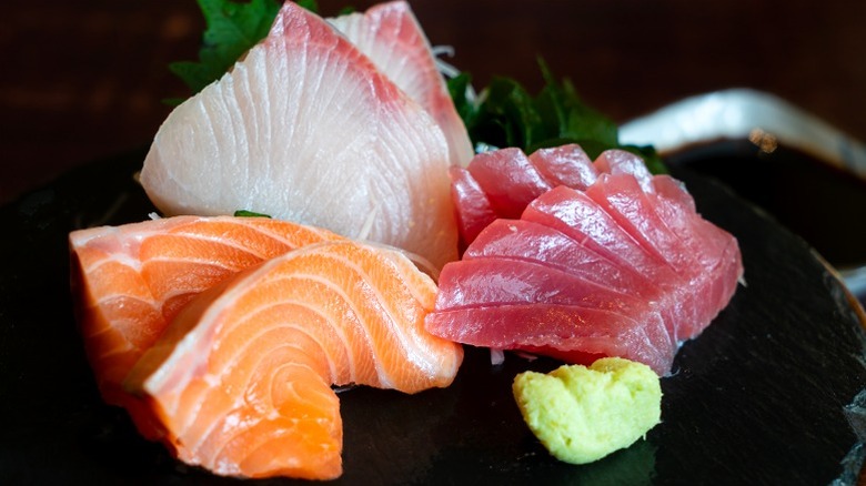 Various cuts of sashimi on plate with wasabi and garnish