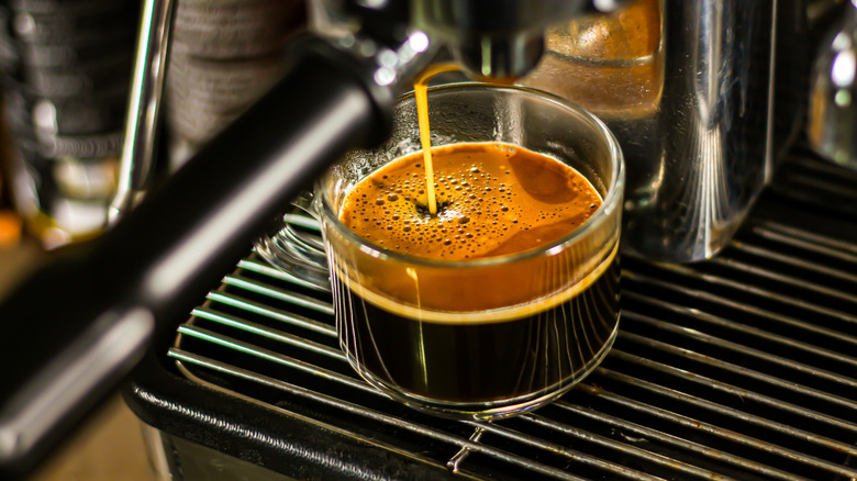 espresso being pulled from an espresso machine into a small glass