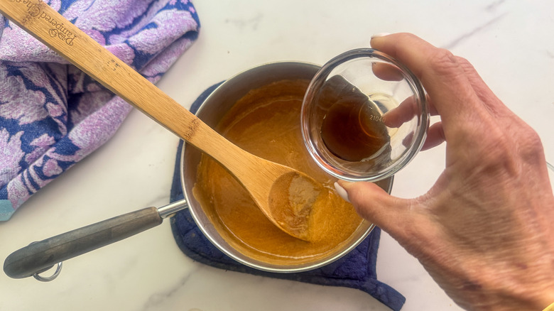hand adding vanilla to pot