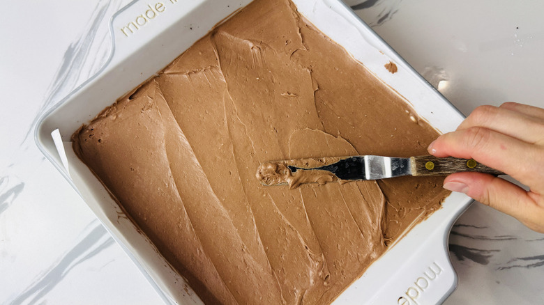 Spreading chocolate no-bake cheesecake in baking pan