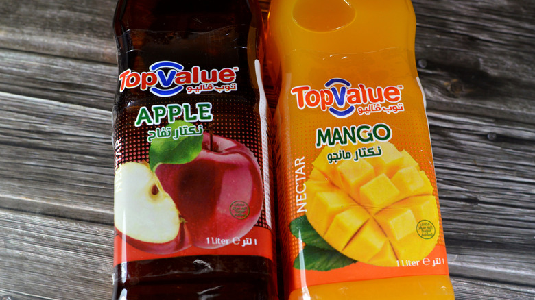 Bottles of apple and mango fruit nectar laying on a wooden surface