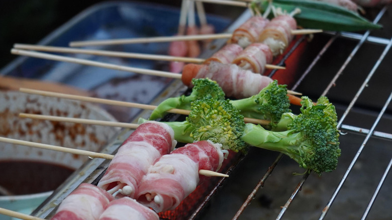 Broccoli cooks on a grill alongside other items.