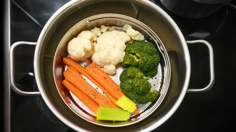 Mixed vegetables steaming in a covered pot.