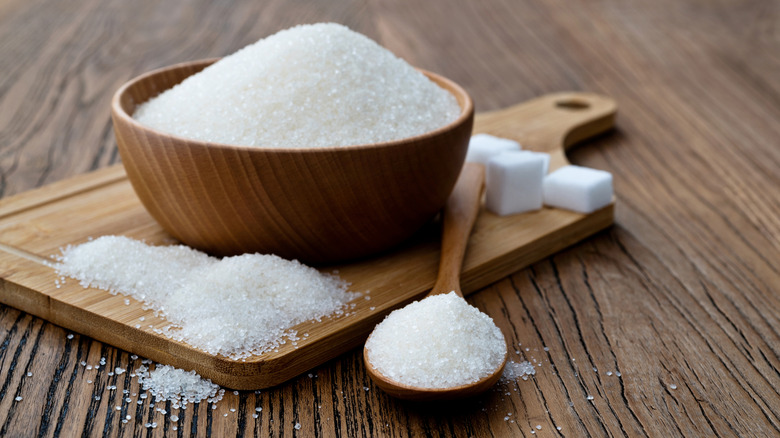 A wooden bowl filled with granulated sugar.