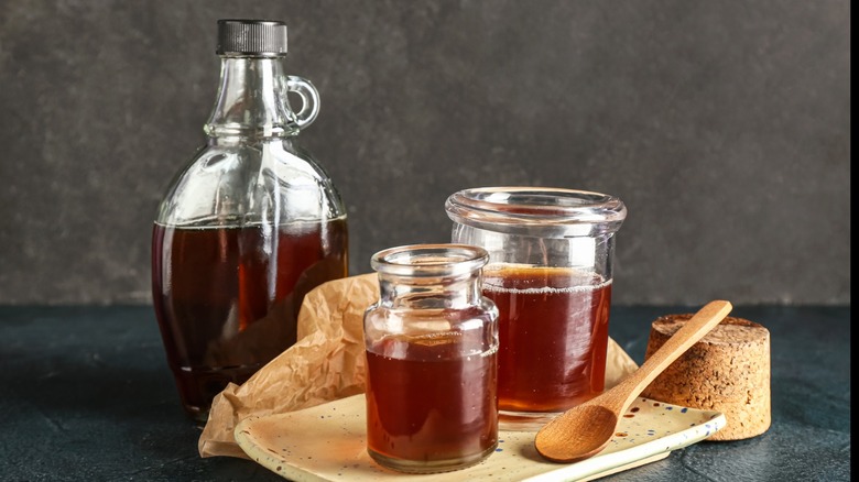 Several jars of maple syrup with a wooden spoon.