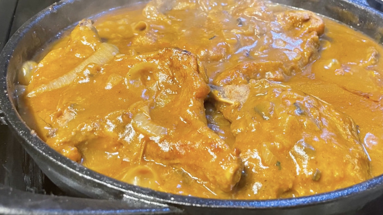 Smothered pork chops with golden mushroom soup in pan.