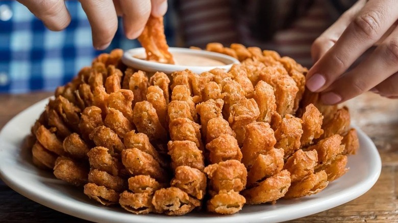 Two people eating a Bloomin' Onion from Outback Steakhouse