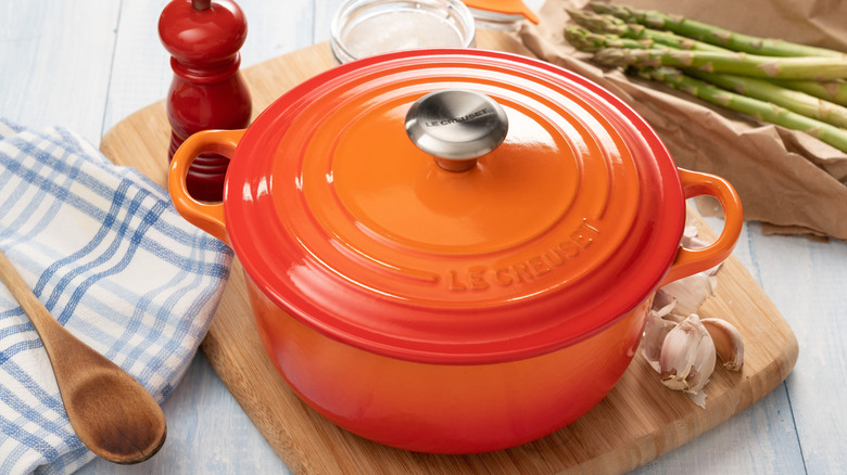 Le Creuset pot on a wooden board with garlic and other ingredients