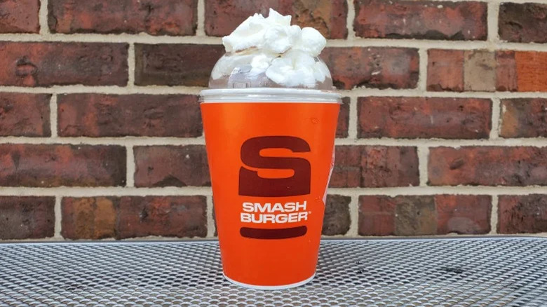 A Smashburger milkshake in front of a red brick wall.