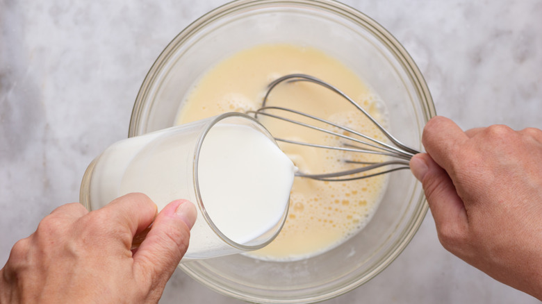 Whisking cream into raw eggs.